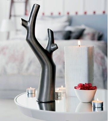 盛满红色糖果的骨瓷碗，搭配白色蜡烛与现代感十足的树形花瓶，冷色中的一抹红色格外打眼。烛光下，方形蜡烛肃静的单纯让空间充满古典的纯净意味。
