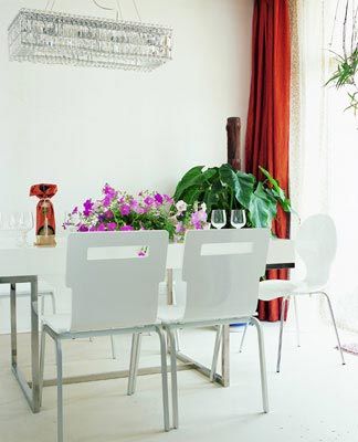 客厅与餐厨空间是开放贯通的白色的钢架桌椅剔透的水晶吊灯和酒具一捧盛放的鲜花格外养眼