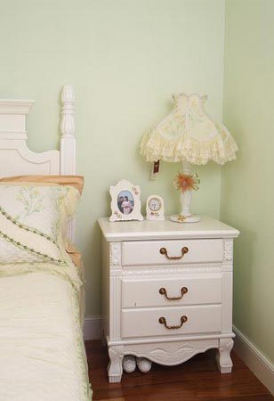 卧室里，蕾丝的台灯，白色田园风格的床台柜和床具，能让人的心情变得舒畅起来。