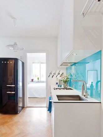 整体白色的厨房空间里，大量的单一色彩未免显得过于空洞和寡淡，而背景墙上小范围地运用淡蓝色玻璃进行搭配，让此墙面一跃成为视线的焦点