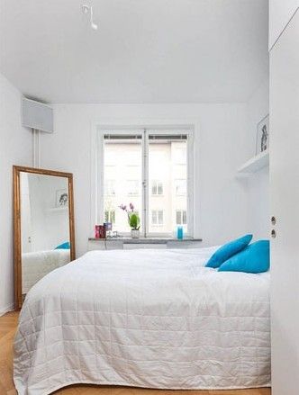 一张素色的大床，配合蓝色的靠包和各种简洁造型的家具，整体风格亲切柔和，让卧室显得温馨而极具幸福感