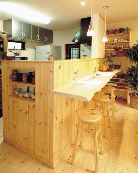 厨房和客厅之间用木制吧台作为分隔，吧台侧边，还充分利用空间地隔了个小柜，摆放茶壶器皿，原木材质的吧台和圆凳让人感觉十分清新