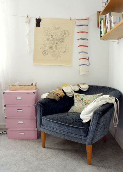 墙角的位置放了配套的单人灰蓝色沙发，搭配粉红色的四层收纳抽屉，呼应大沙发上的很红色
