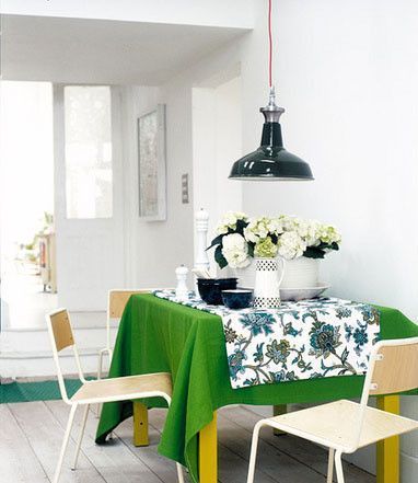 把小餐桌靠墙而放，节省了不少空间。草绿色的餐桌底布和带大花朵图案的餐桌布相搭配，营造出了浓浓的田园气息