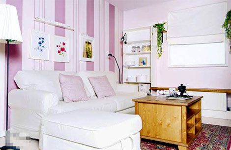 客厅的墙面用粉红色壁纸铺贴，与白色的家具相互呼应；沙发为宽大的白色双人沙发
