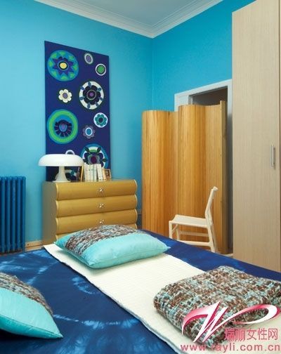 深蓝色调的装饰画与床品丰富了空间的层次感