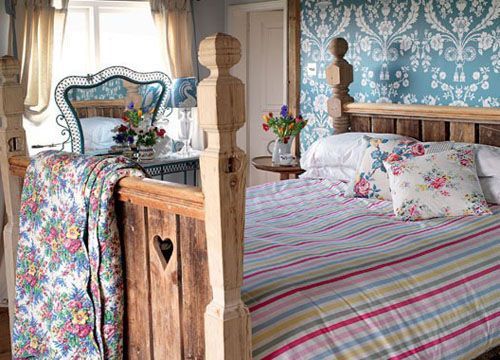 床头背景墙精美的壁纸设置跟粗糙的木床形成鲜明的对比，很舒适的乡村卧室装扮