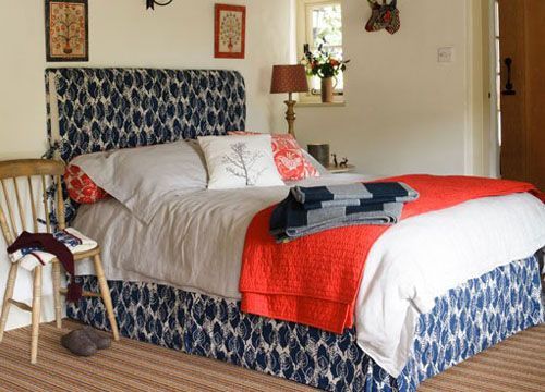 一张大大的床摆在最中间，青花瓷版的布衣床架搭配白色的床单和红色披毯，视觉冲击力十足，营造出整个室内的视觉中心
