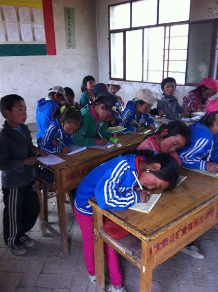 青海藏区孩子们挤在几张课桌上上课