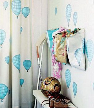 壁纸和窗帘选用了同一系列的花色，乳白色的背景下，浅淡的天蓝色热气球三两成群地飘过。墙壁上棉布材质的收纳袋顽皮可爱