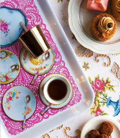 镂空桌布搭配鲜艳的花朵图案，可爱的小茶杯和色彩明艳的小托盘让人不禁想起那幢全是糕点和糖果组成的屋子