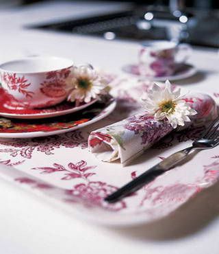 鲜花可以做成别致的餐巾扣，用丝线将一朵白色菊花系在印有红色花朵图案的餐巾上，美丽的餐巾扣即刻呈现在眼前，为用餐环境带来别样惊喜