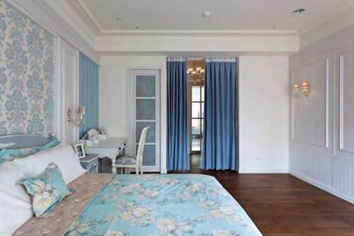 走以淡灰蓝色系的主卧房，床头段落以英式风格壁纸搭配，藉由线板中和表现段落个性画面