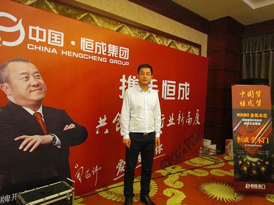 恒成集团董事长胡晓林在企业宣传背景墙前留影